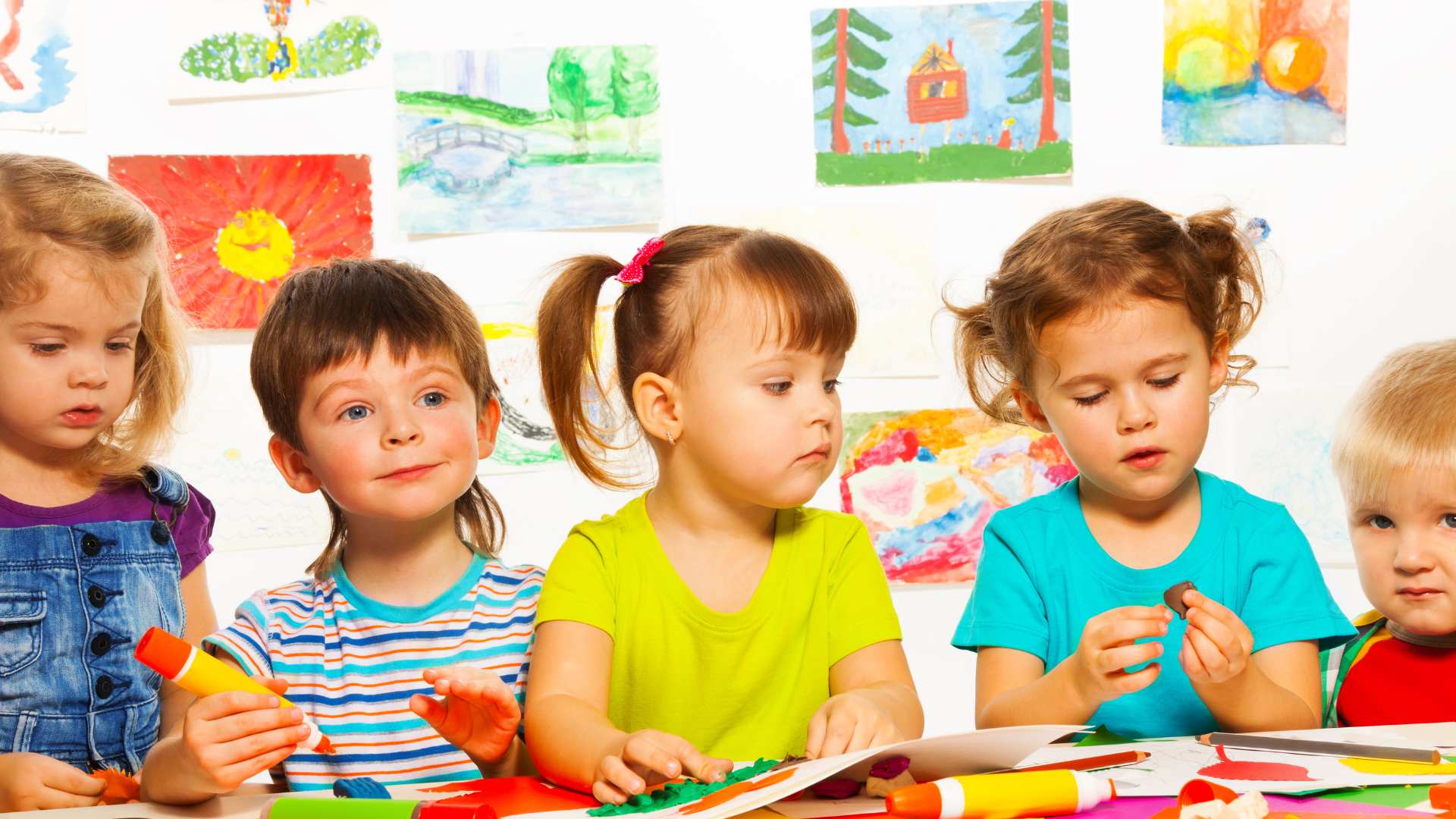 A group of young children sitting at a table doing colorful craft activities