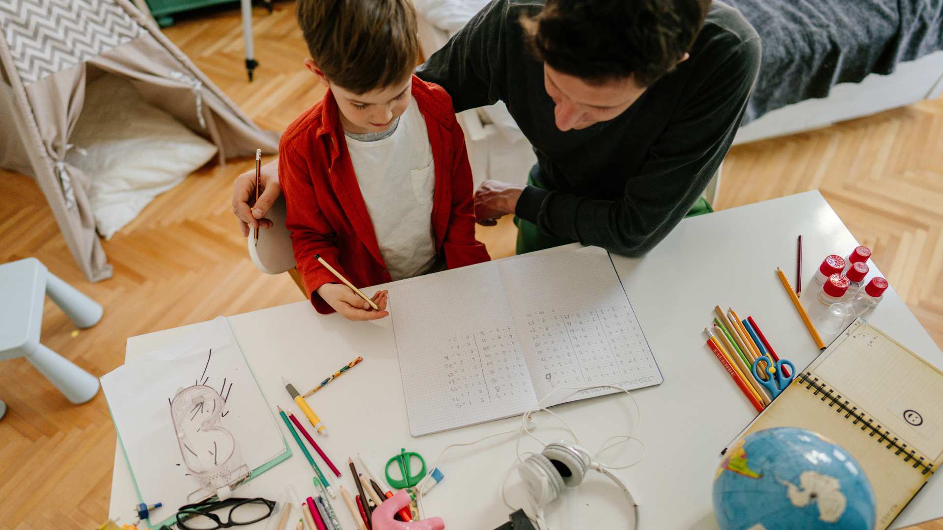 A parent guiding a child through schoolwork at home, showing a calm moment of homeschooling a child with autism