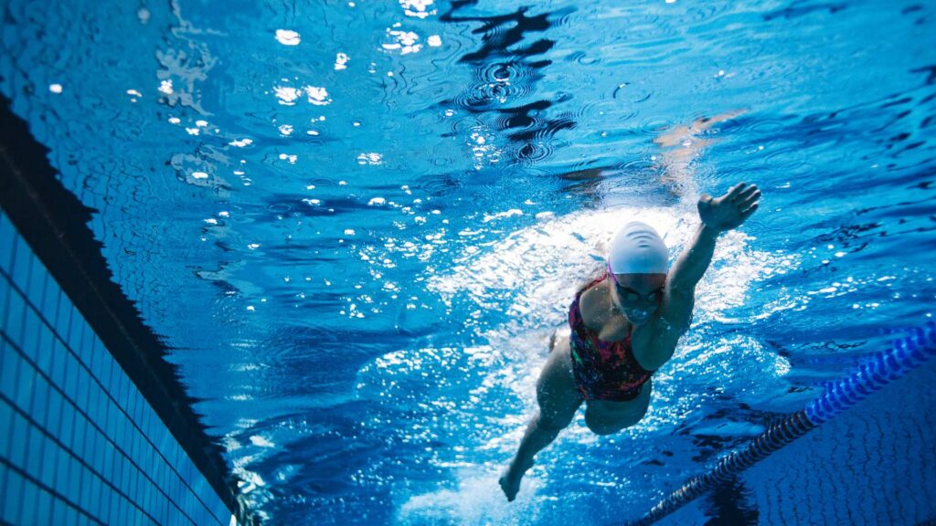 A swimmer moves with focus through a pool, reflecting the discipline and determination shown by athletes with autism.