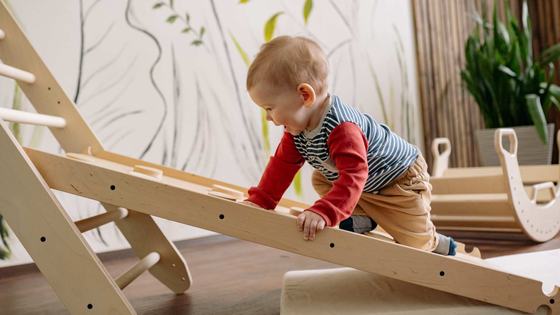 A young child pulling themselves up a ramp, showing balance, curiosity, and growing independence around 18 months