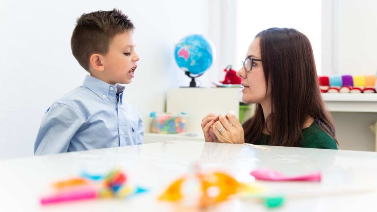 A young kid and a therapist interacting to highlight speech delay vs autism