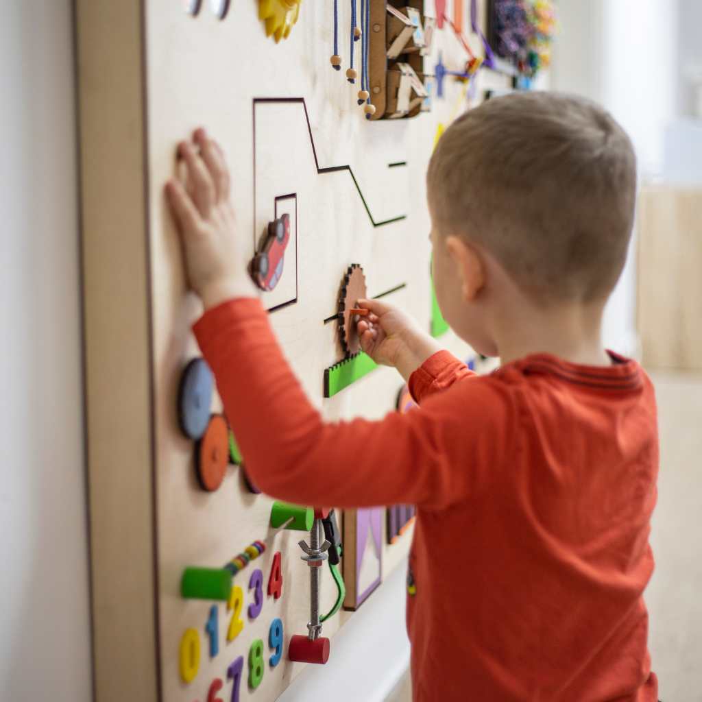 Child engaging with an educational activity board, illustrating how ABA therapy provides supportive resources tailored to individual needs in neurodiversity