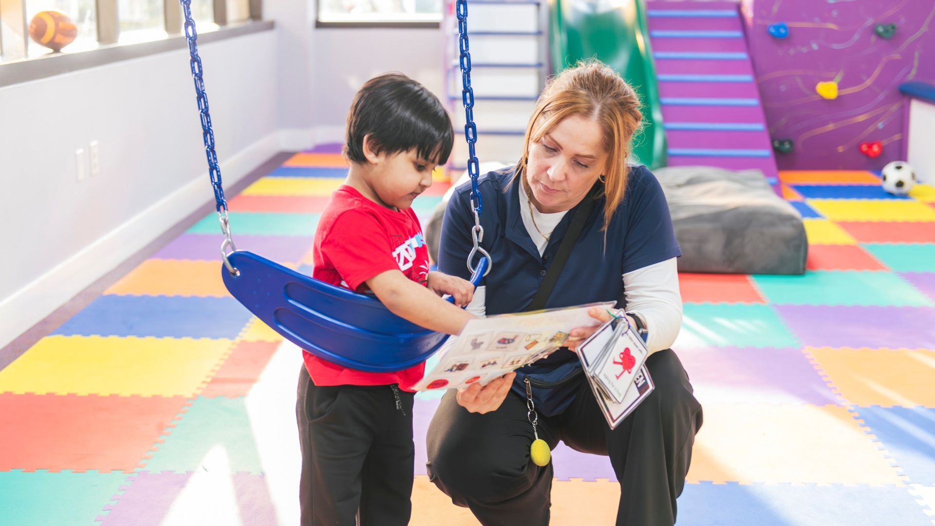 ABA therapist using visual supports to help a young child build communication and learning skills during an individualized therapy session.