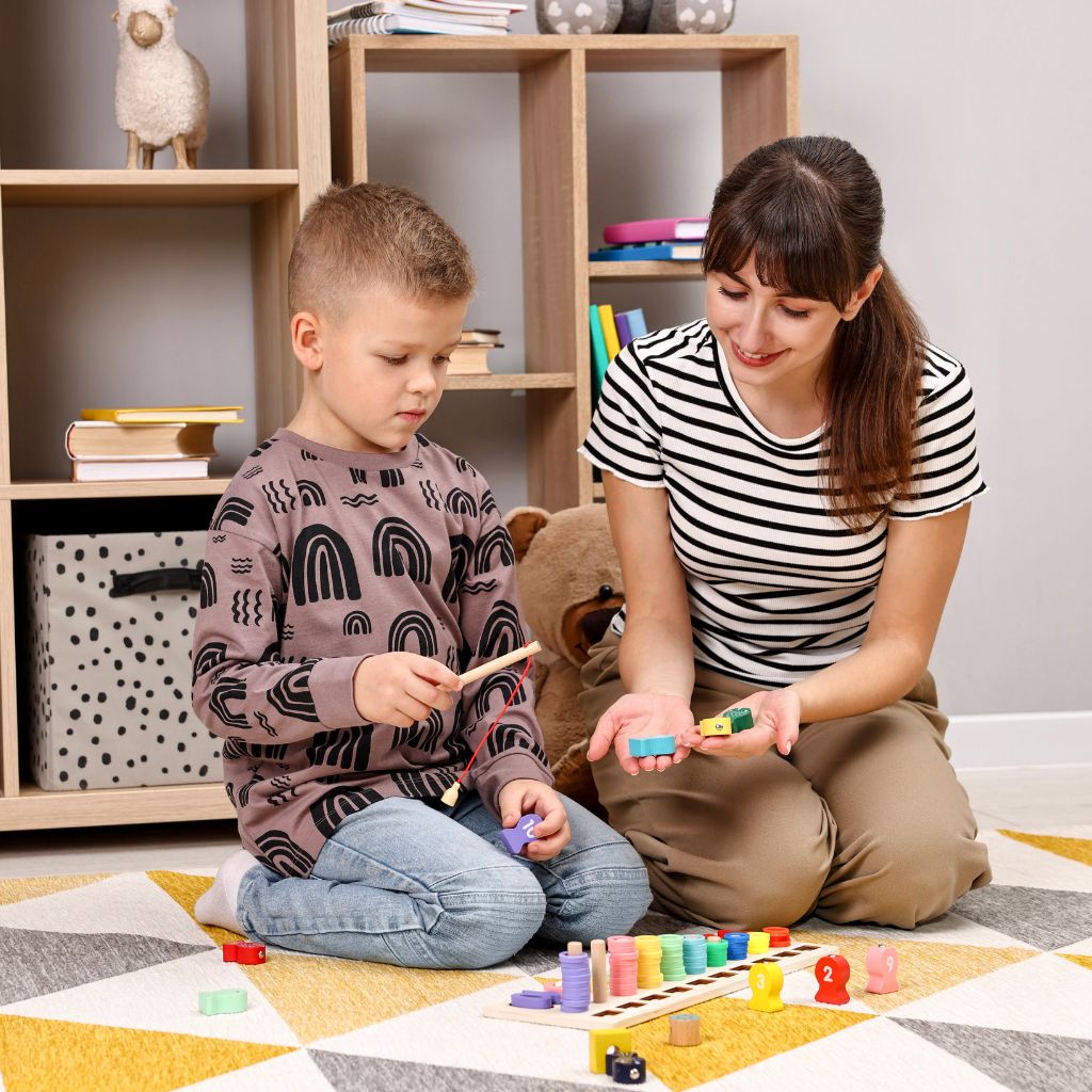 ABA therapist working one-on-one with a young child during a play-based therapy session to build communication, attention, and problem-solving skills.