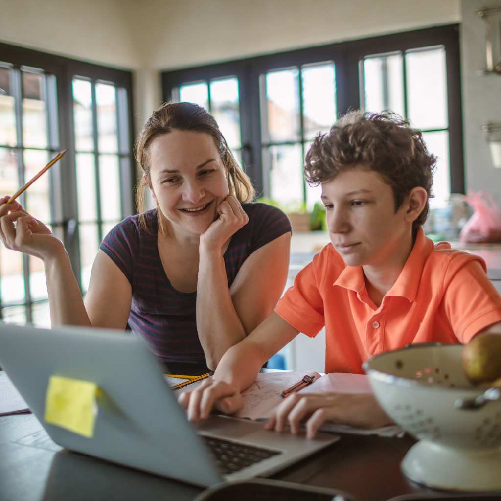 Adult and child working together at a kitchen table illuystrating homeschooling a child with autism