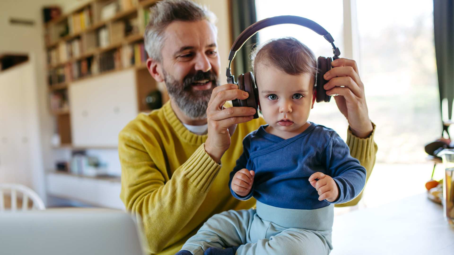Adult holding a toddler while introducing headphones to support their sensory needs
