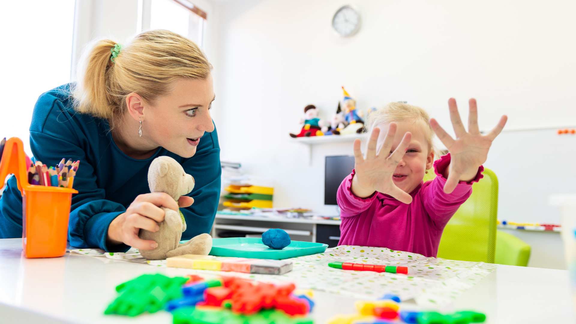 An ABA professional guiding a small child through a hands‑on task at a table