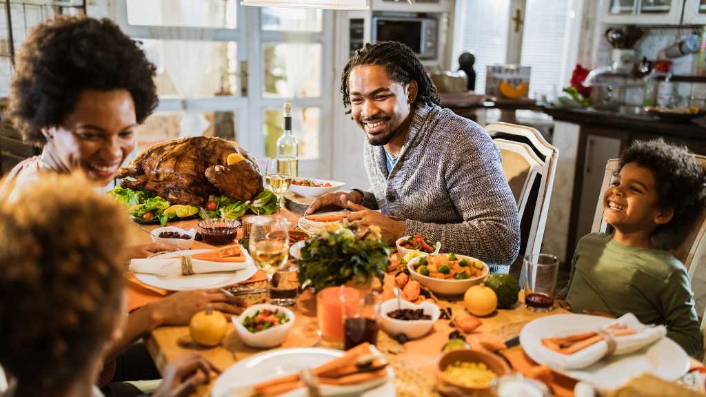 Family enjoying an autism-friendly Thanksgiving meal together, smiling around the dinner table with a roasted turkey and festive decorations.