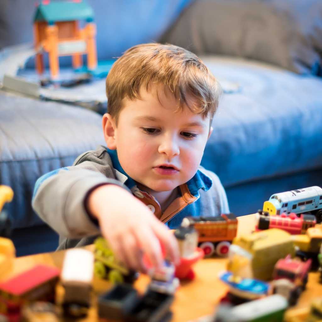 Child playing with toy trains, representing behavioral characteristics and executive function challenges in level 1 autism