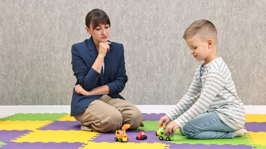 Child playing with toys while an adult watches calmly, showing a moment related to compliance in autism