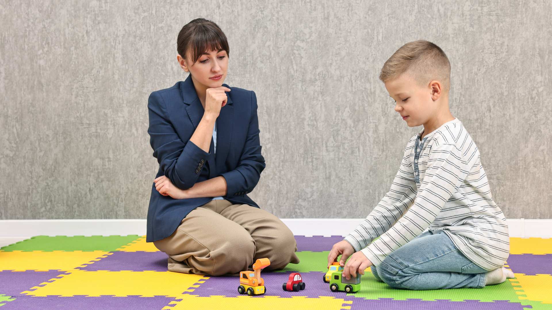 Child playing with toys while an adult watches calmly, showing a moment related to compliance in autism