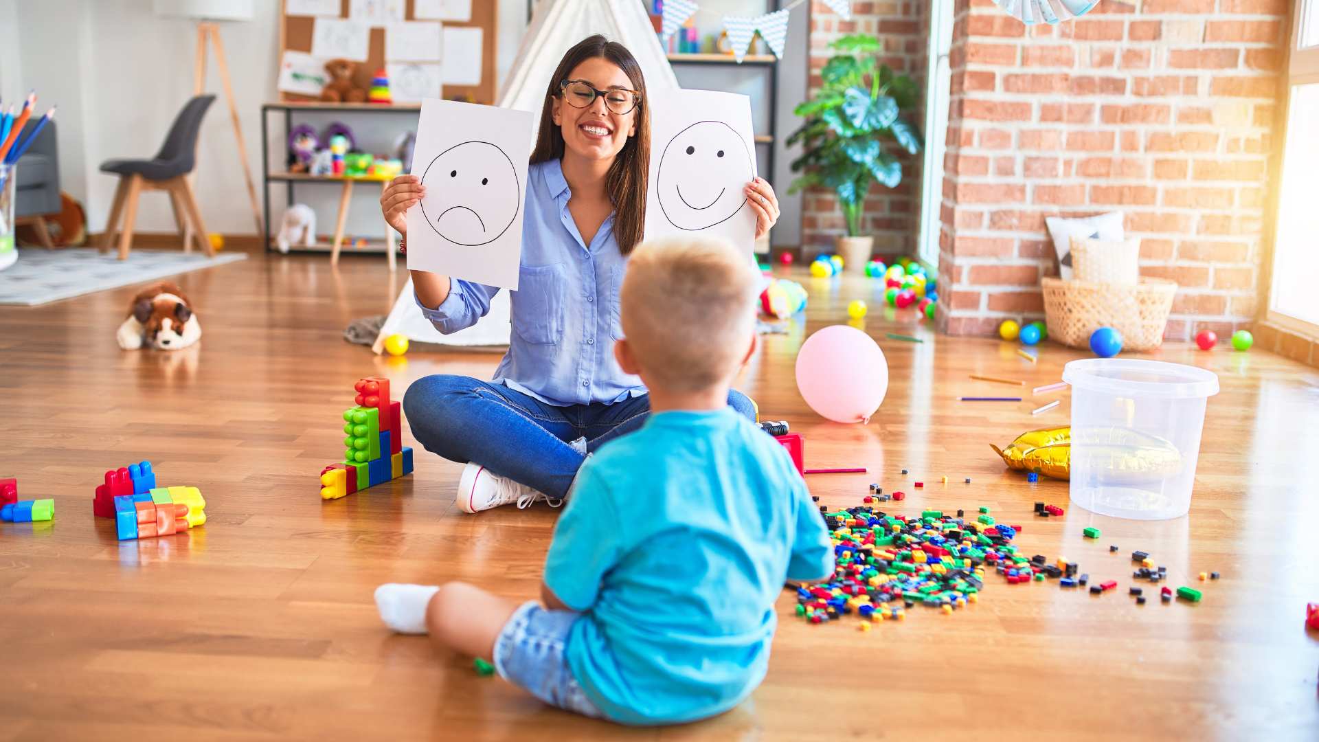 Child sitting on the floor while an adult uses picture cards to teach early communication skills in ABA