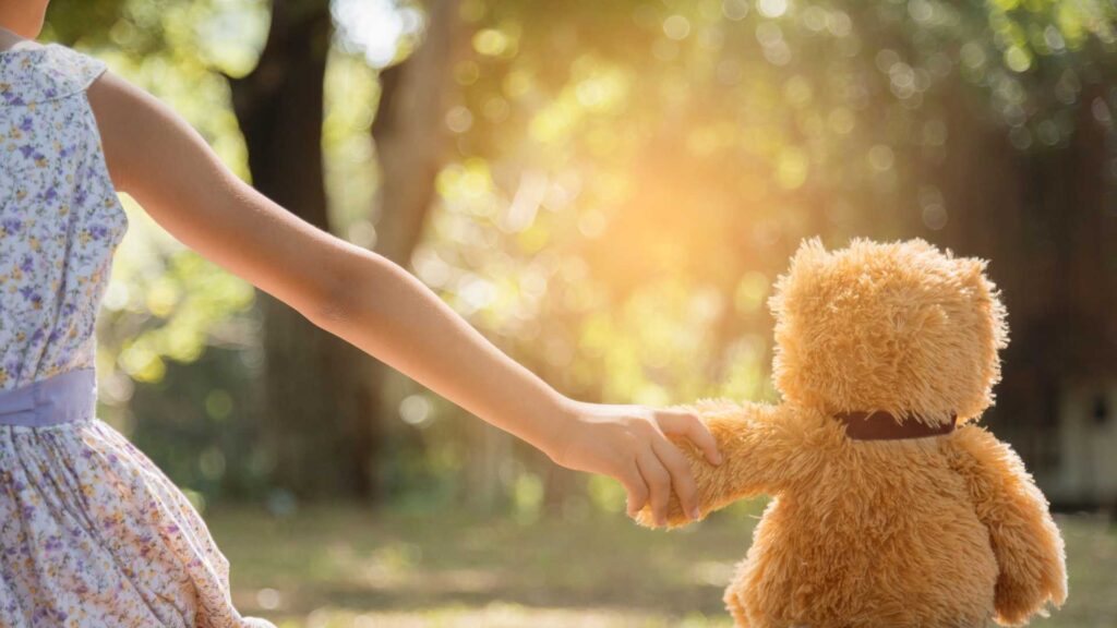 Self-expression and autism: a girl holding a teddy bear's hand.