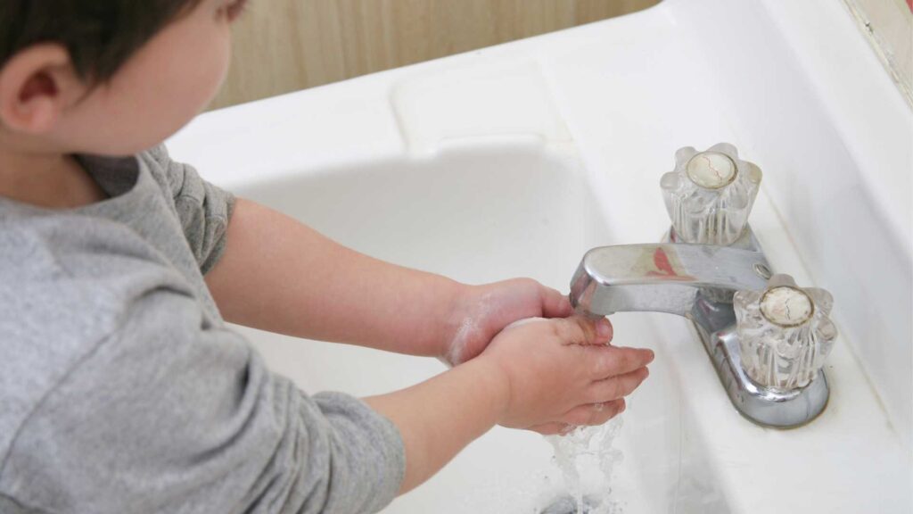 Handwashing and autism: a child maintaining proper hygiene and washing their hands under running water at a sink.