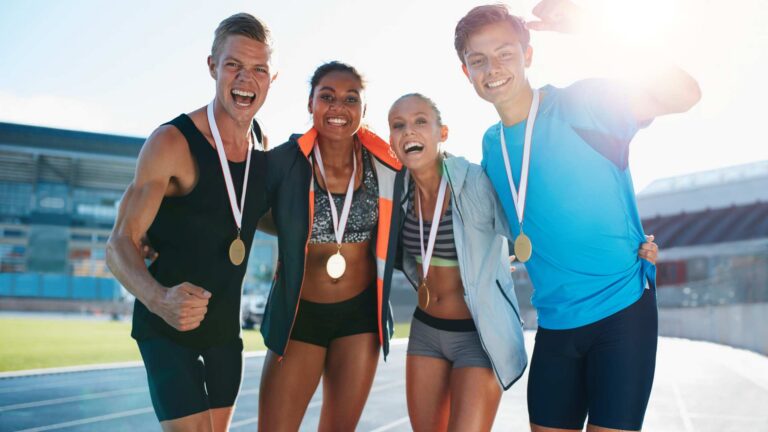 Four runners with medals celebrating in a track, highlighting the positive connection between autism and sports