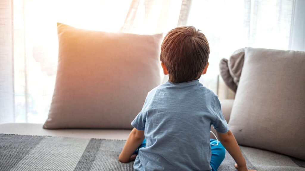 Impact of Environments on Autism. A child looks at a window and a pillow.