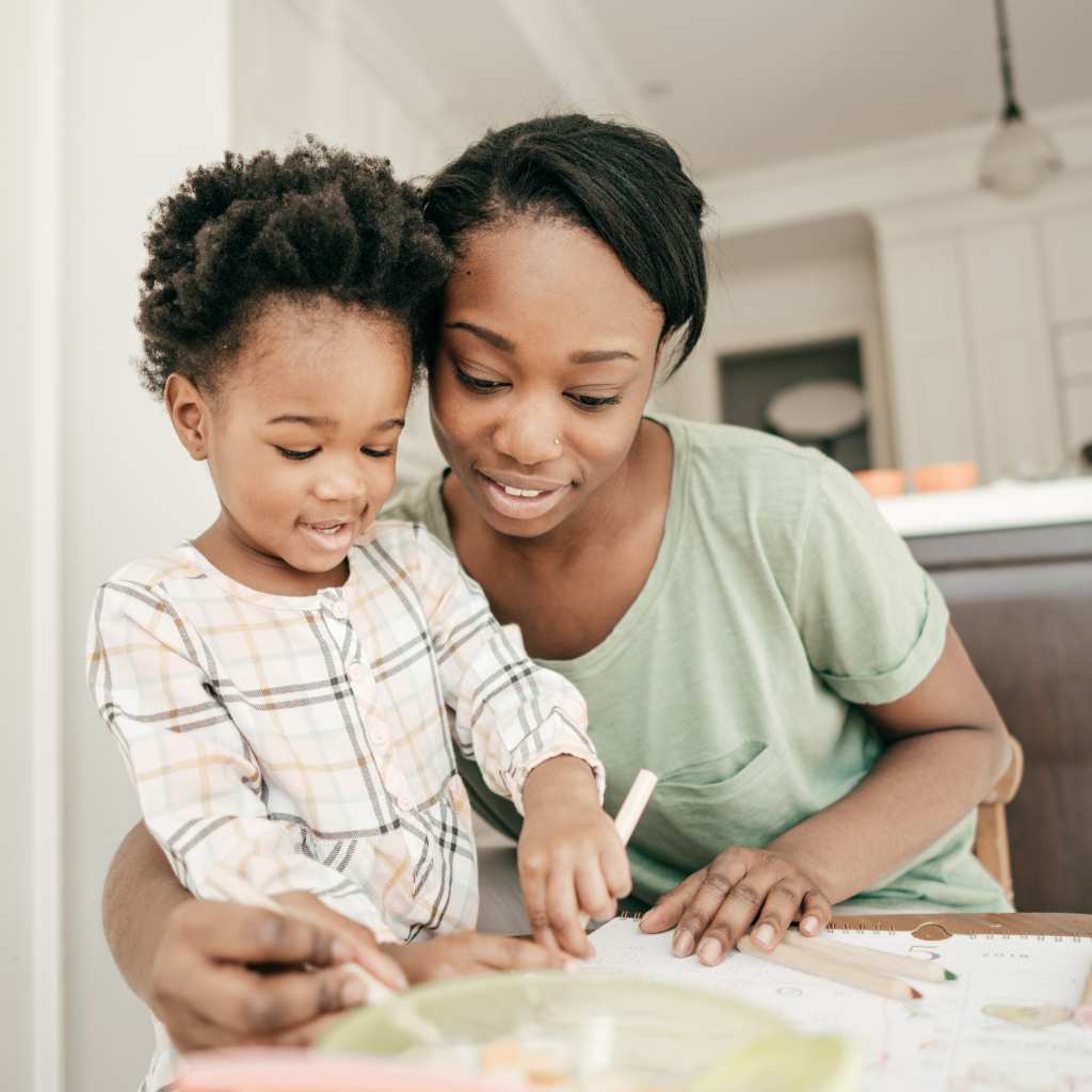 Mother helping her toddler practice coloring at a table, reinforcing learning skills during an ABA therapy activity at home