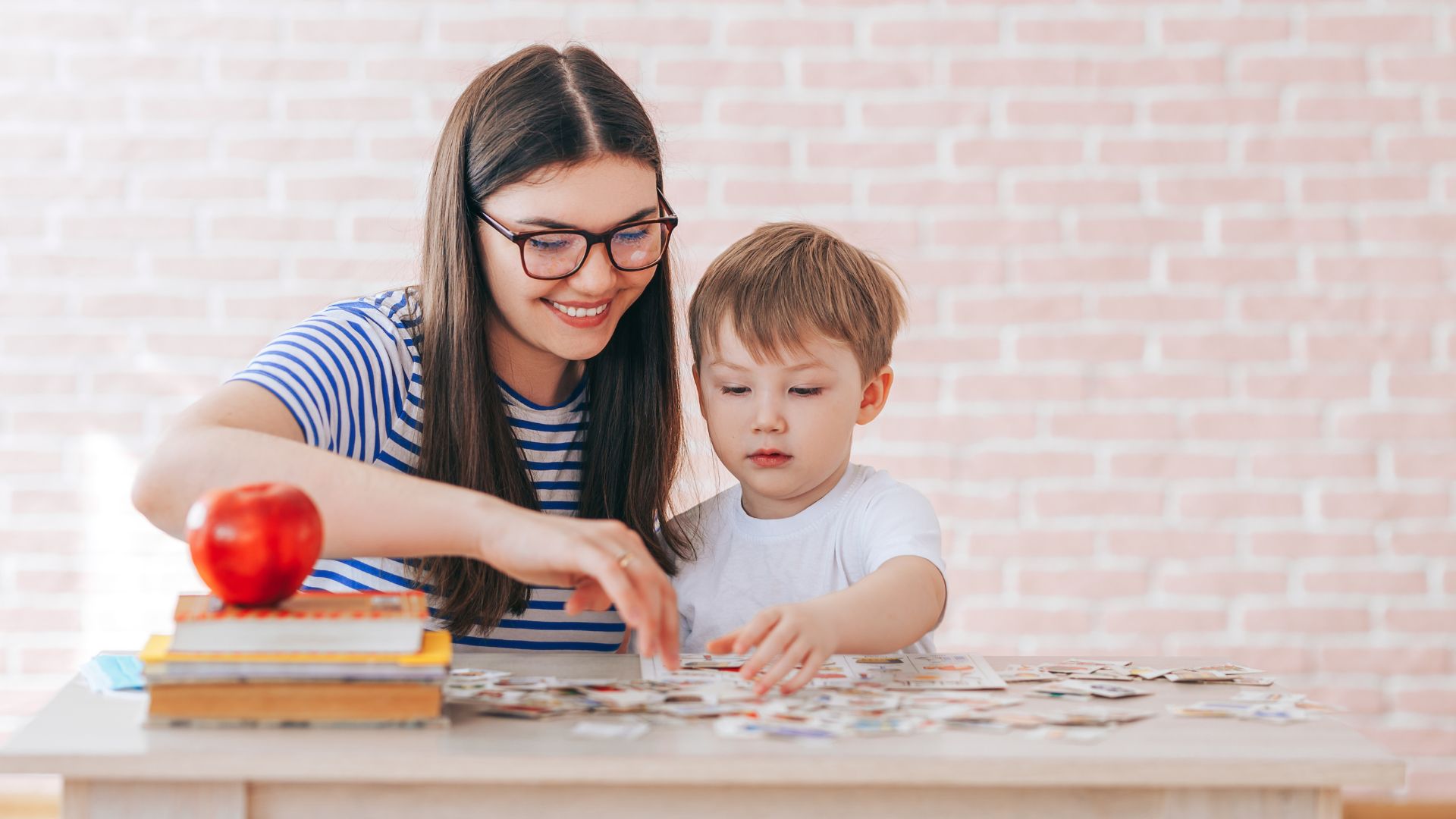 Mother practicing ABA strategies for parents while completing a matching activity with her young child at home.