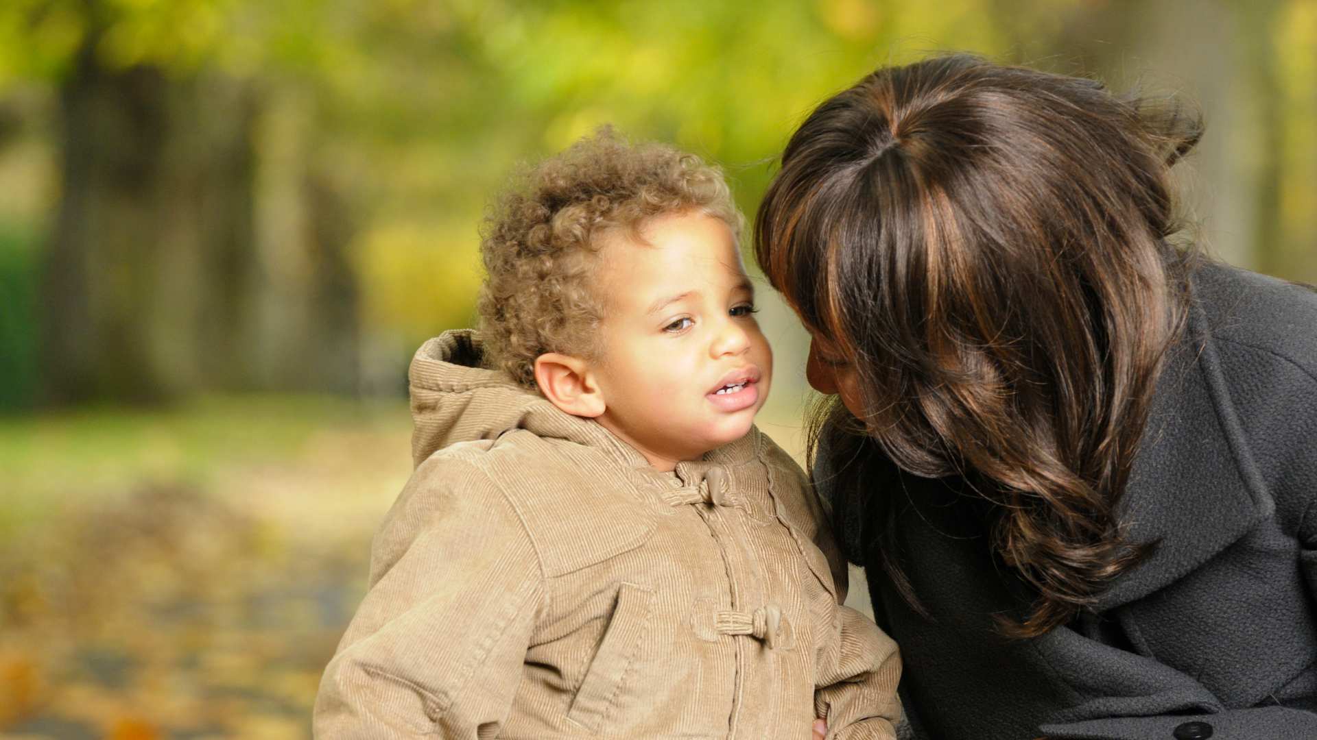 Adult leaning toward a toddler outdoors as the child looks away, relating to My Toddler Doesn't Respond to Their Name