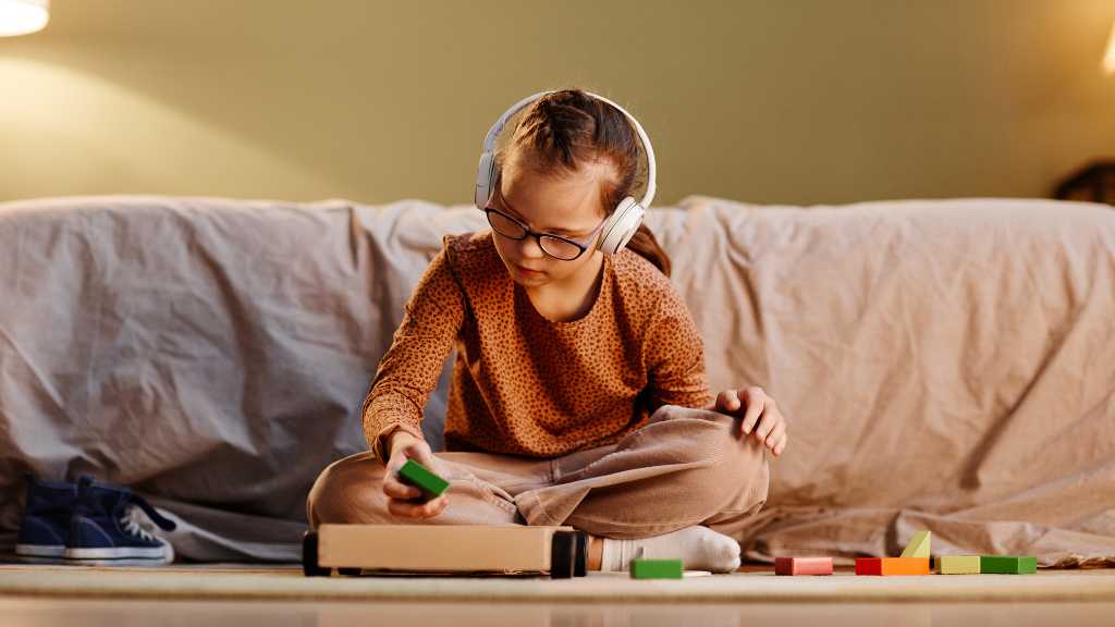 Child wearing headphones and playing with colorful blocks, representing the difference between neurodiverse vs neurodivergent and unique ways of experiencing the world