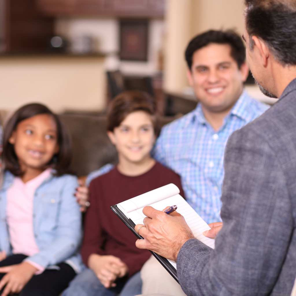 Parents and child having a friendly conversation with an ABA professional on the couch