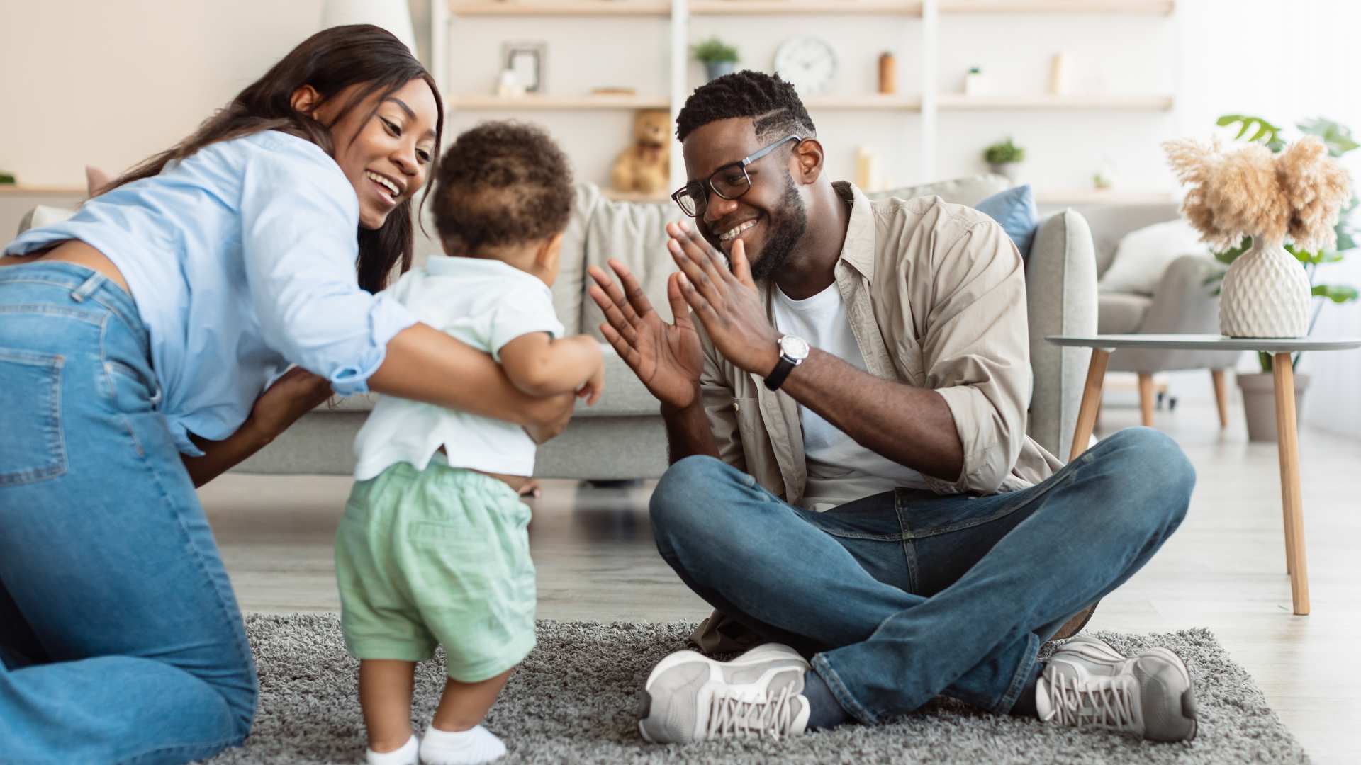 Parents smiling and guiding their baby during a playful learning moment