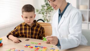 Pediatrician uses colorful letter tiles to assess a young boy's developmental skills during an early autism diagnosis evaluation