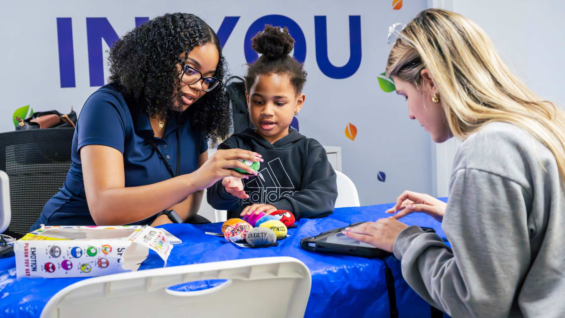 Child engaged with bright toys while an adult guides learning in an ABA-style session