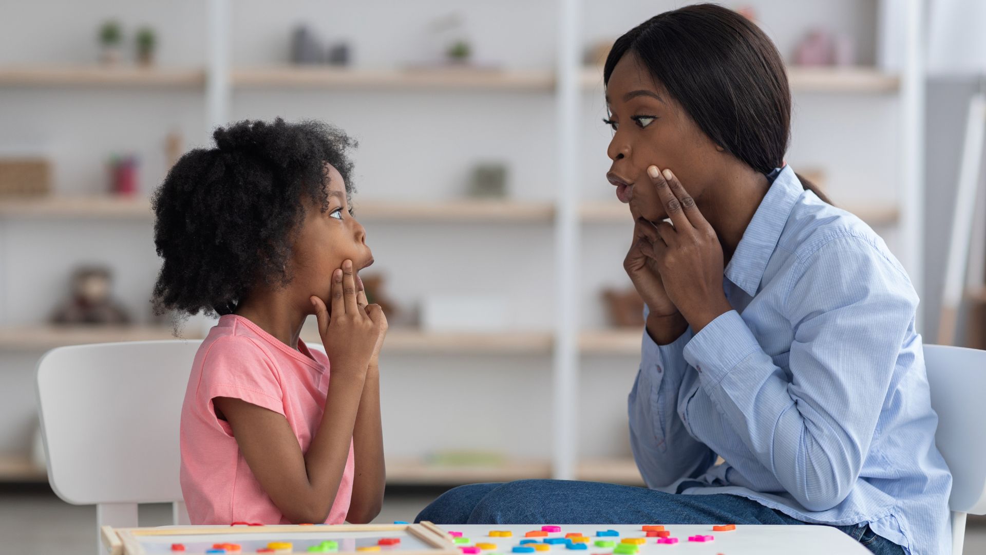 Speech-language pathologist helping a child practice speech sounds and mouth movements during a speech therapy session.