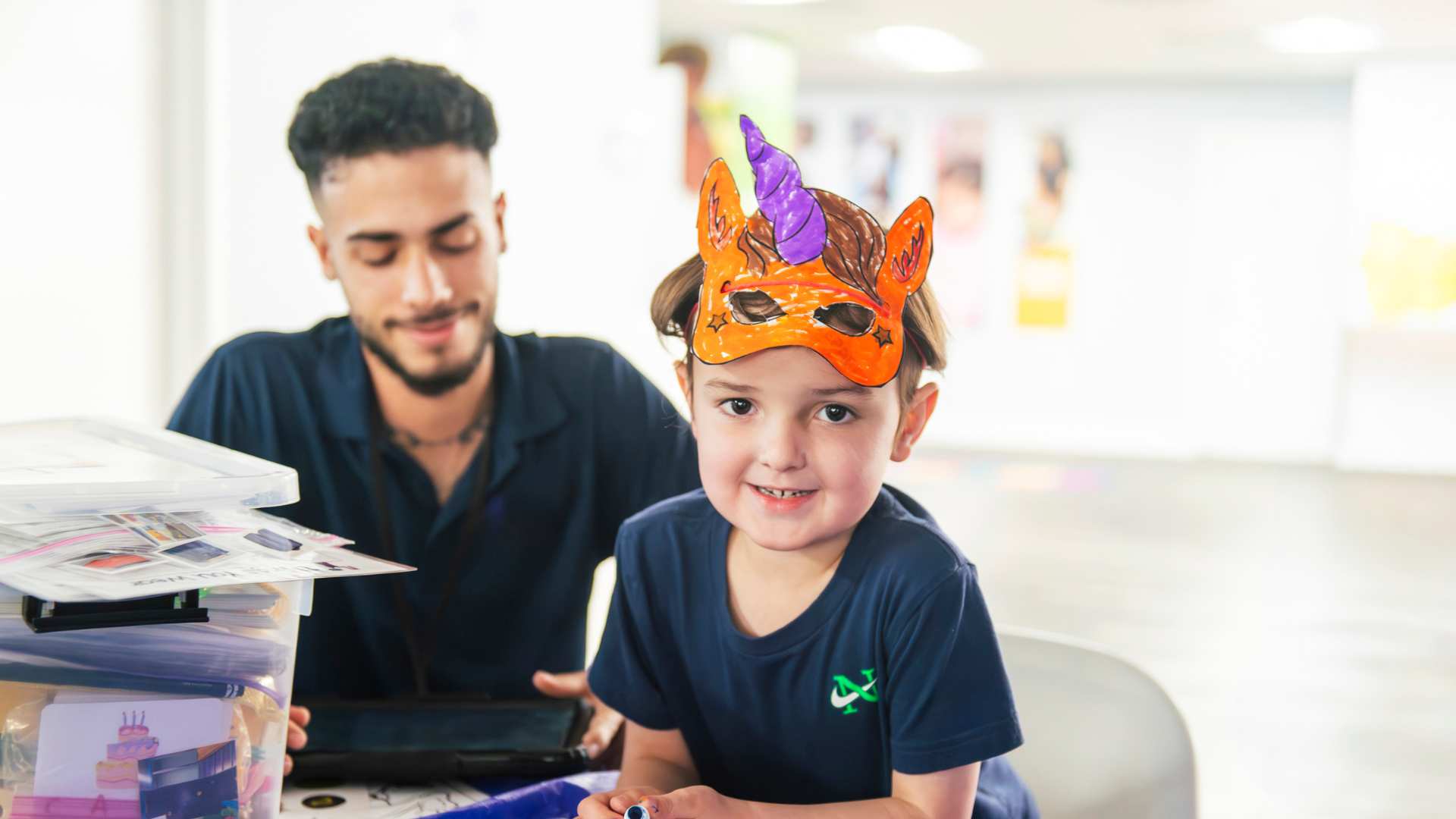 Toddler wearing a colorful mask while doing a playful activity with an ABA professional during an ABA session