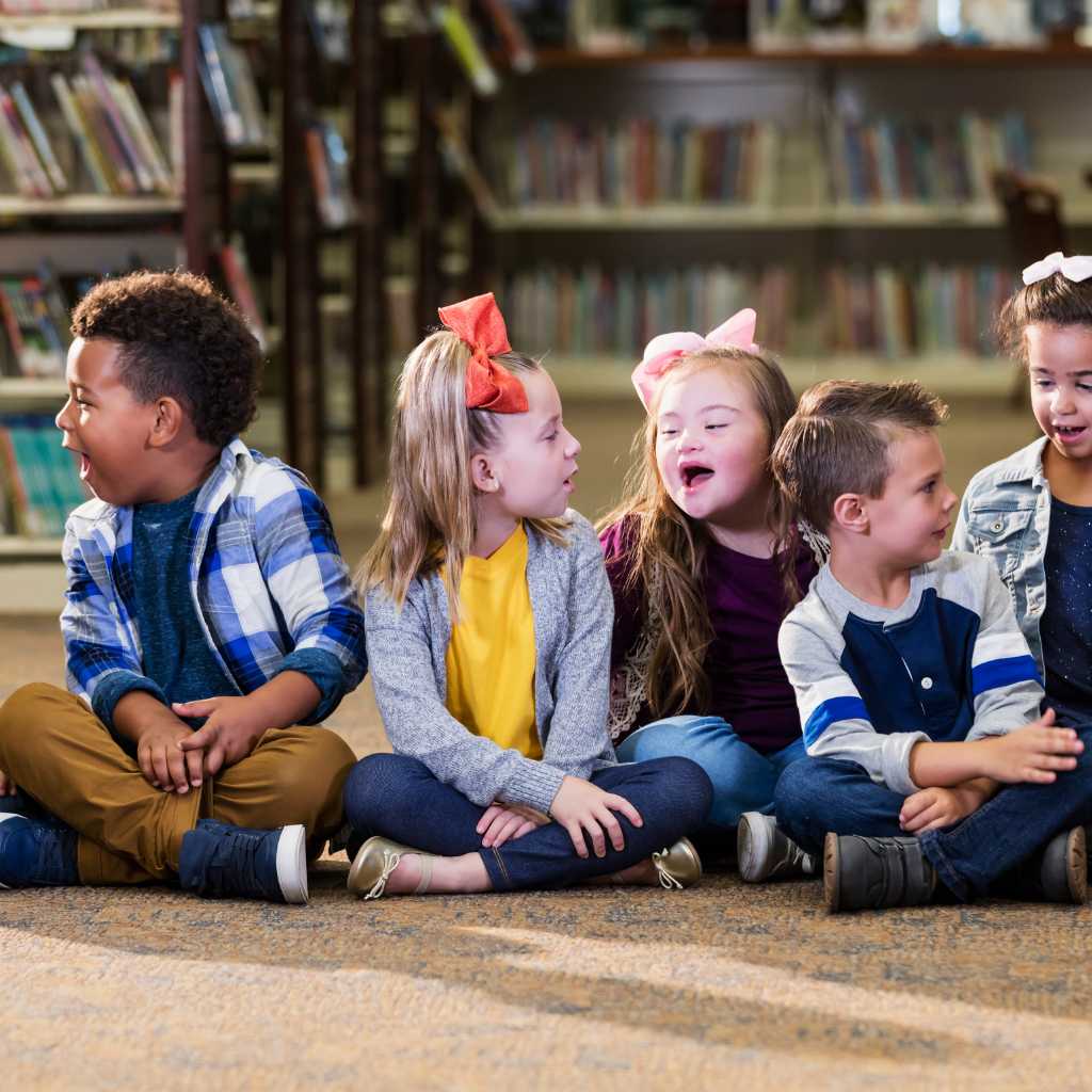 Group of young children with diverse abilities sitting together in a library, illustrating what is neurodiversity and the value of human difference
