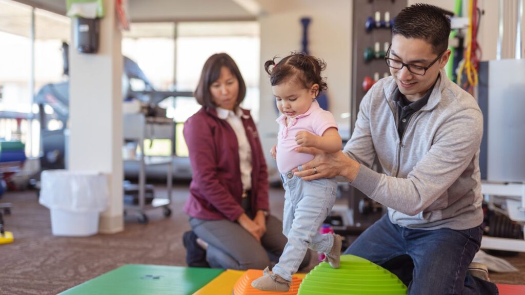 ABA Therapist helps a young girl walk across balance balls
