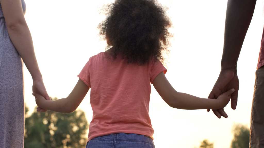 Parents holding hands with child outdoors – illustrating the support for the autism window of tolerance.