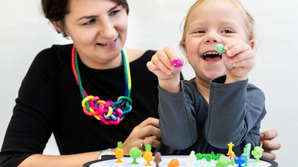 Woman and child play together with toys as part of autism support.