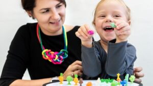 Woman and child play together with toys as part of autism support.
