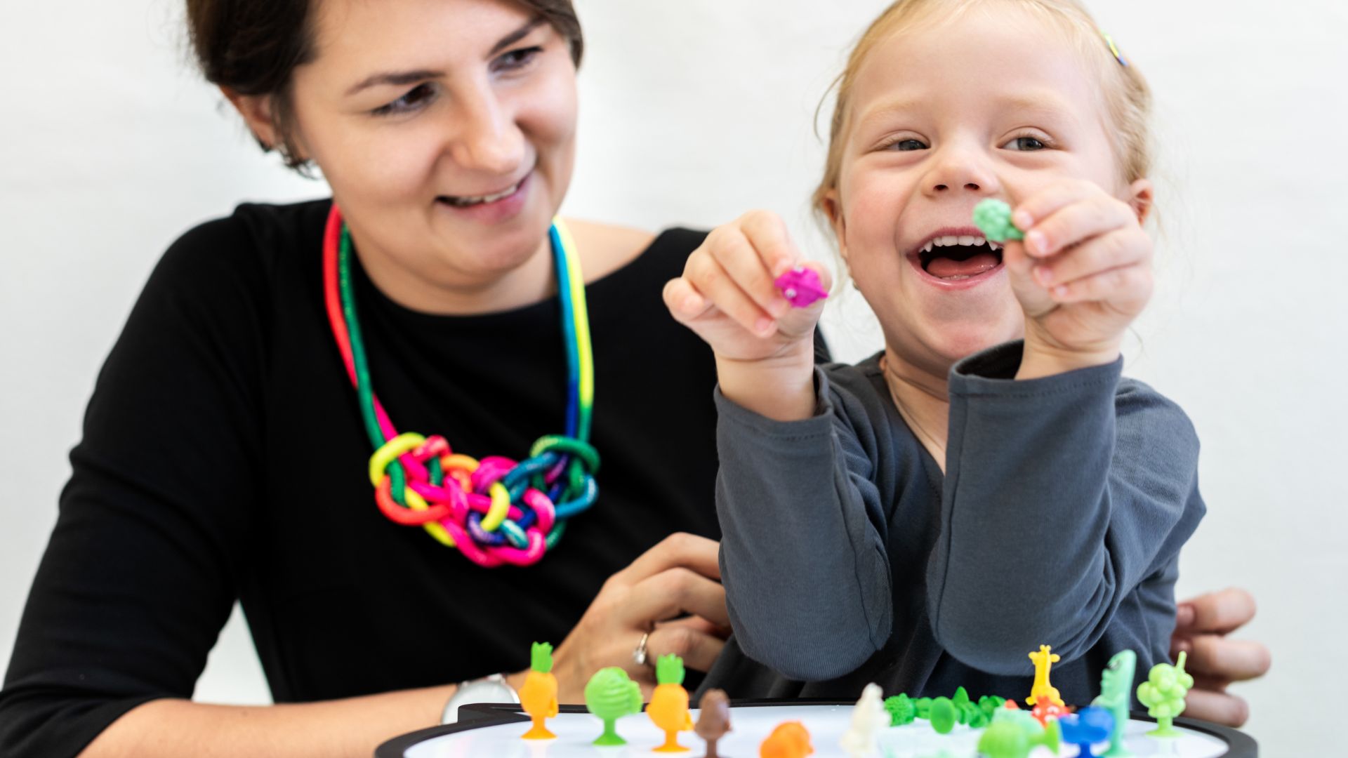 Woman and child play together with toys as part of autism support.