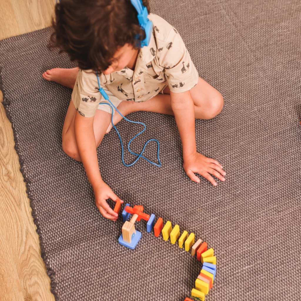 Young child lining up bright toy blocks on the floor