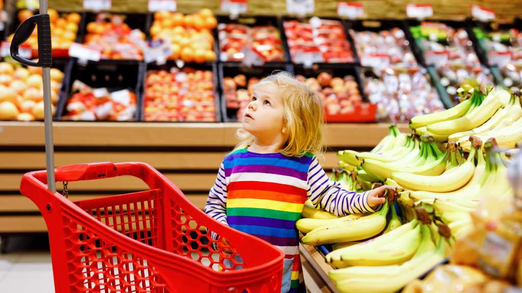 Young child choosing bananas at a grocery store to practice decision-making skills